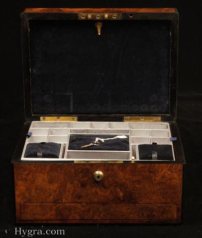 Antique ebony edged  box in highly figured burr walnut having a Bramah type lock and  a sprung drawer of dovetail construction fitted for jewelry and a lift out tray. The drawer is held in place by a brass pin driven through the facing. In the top section there is a lift-out compartmentalized tray. In the lid there is a document wallet. Circa 1860. -Enlarge Picture